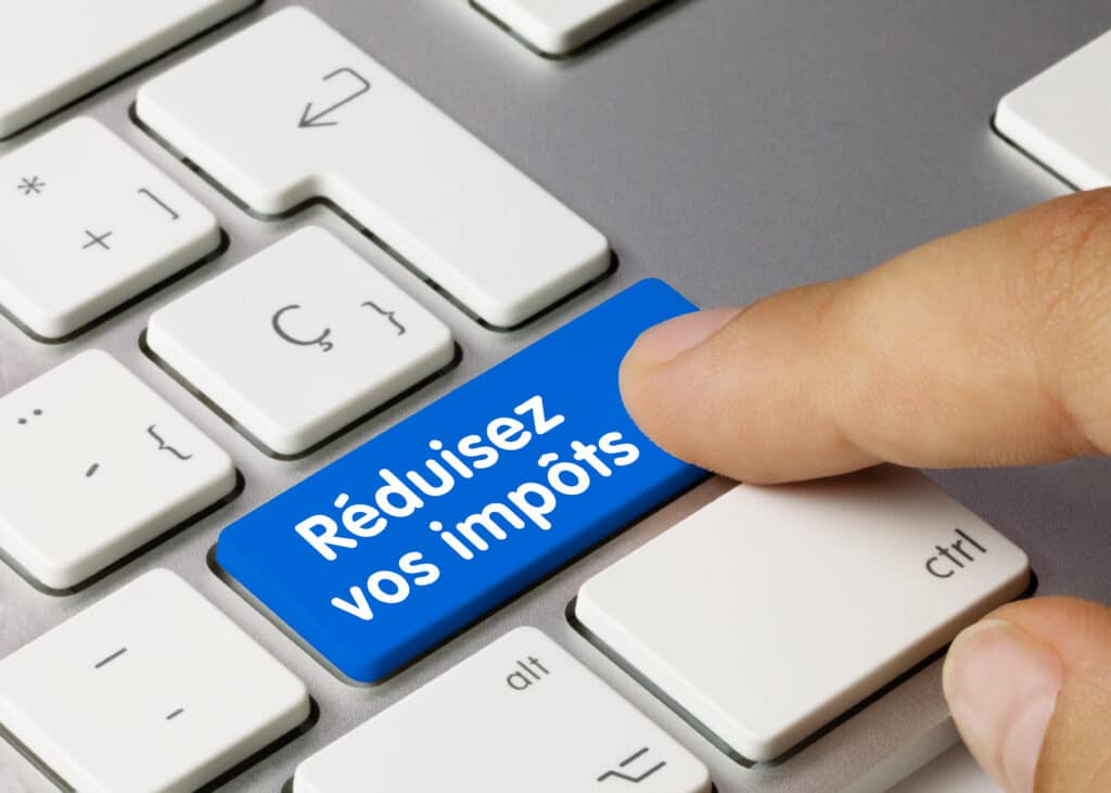 Doigt pressant une touche bleue de clavier affichant le texte blanc "Réduisez vos impôts".